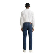 Dunkelblaue Jeans mit klassischem Fünf-Taschen-Design und dezenter Waschung, kombiniert mit einem Gant-Herrenhemd