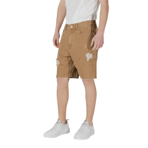 Brown distressed cargo shorts with multiple pockets and a white t-shirt underneath.