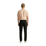 Ein Mann, der Gianni Lupo Schwarze Herrenhose aus Polyester-Viskose, kombiniert mit einem hellpfirsichfarbenen Kurzarmhemd