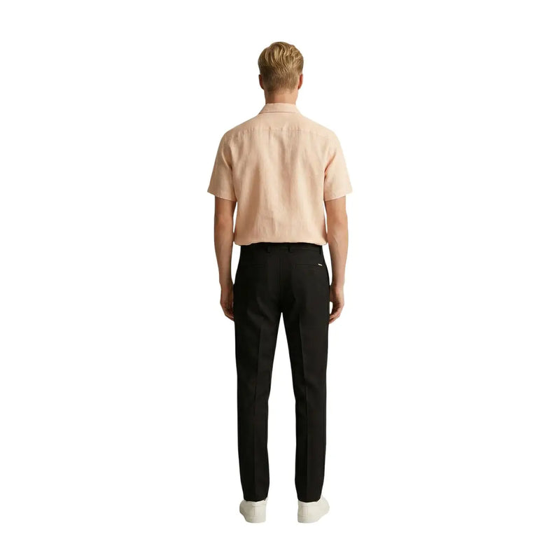 A man wearing Gianni Lupo men black polyester viscose trousers paired with a light peach short-sleeved shirt