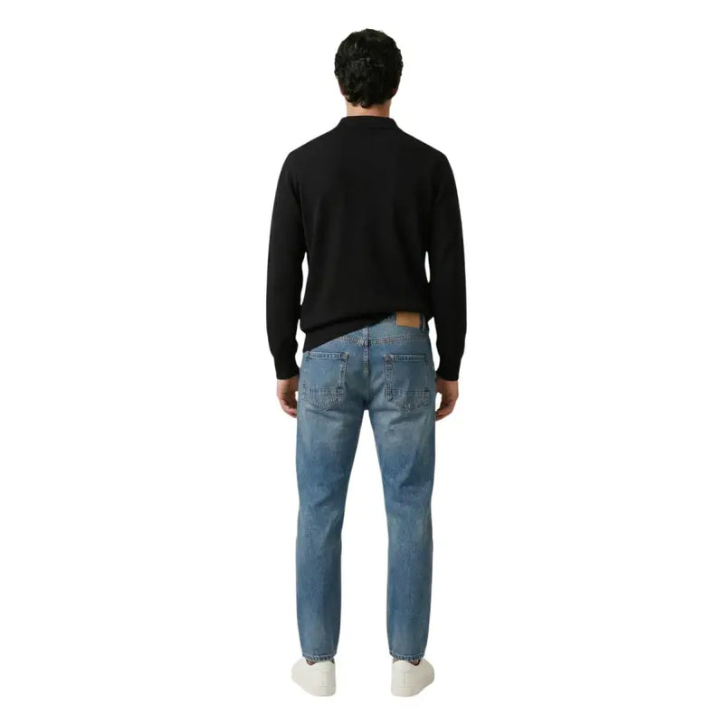 Eine mittelblaue Jeans mit braunem Leder-Markenaufnäher am hinteren Bund von gianni lupo
