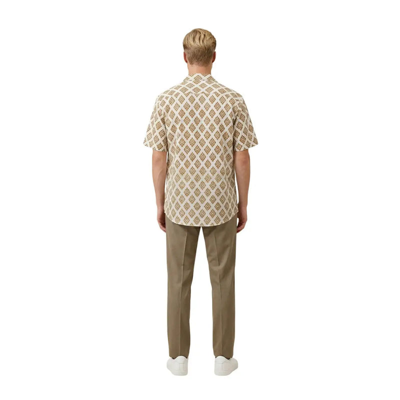 A man wearing a beige Gianni Lupo men shirt with a repeating brown and cream geometric pattern and short sleeves