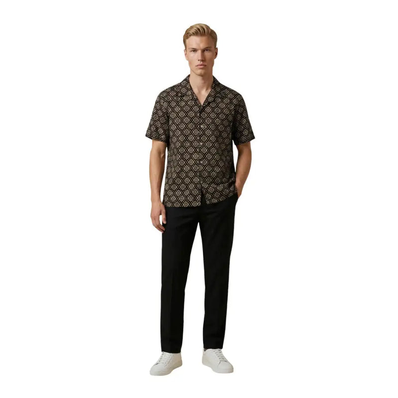 Ein Mann, der einen Gianni Lupo Schwarzes Herrenhemd mit aufwendigem goldenem geometrischem Muster und kurzen Ärmeln