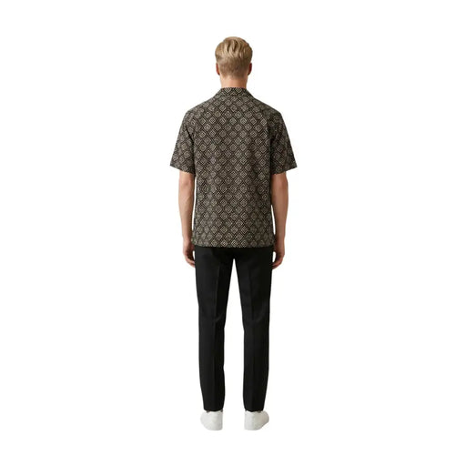 Ein Mann, der einen gianni lupo Herrenhemd in Dunkelbraun mit aufwendigem goldenem geometrischem Muster und kurzen Ärmeln