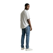 Ein Mann, der einen gianni lupo Weißes Rundhals-T-Shirt aus 100 % Baumwolle kombiniert mit mittelblauen Jeans.