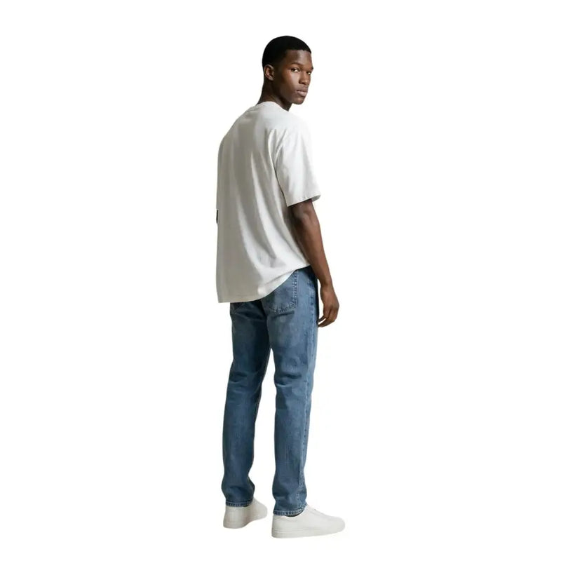 Ein Mann, der einen gianni lupo Weißes Rundhals-T-Shirt aus 100 % Baumwolle kombiniert mit mittelblauen Jeans.