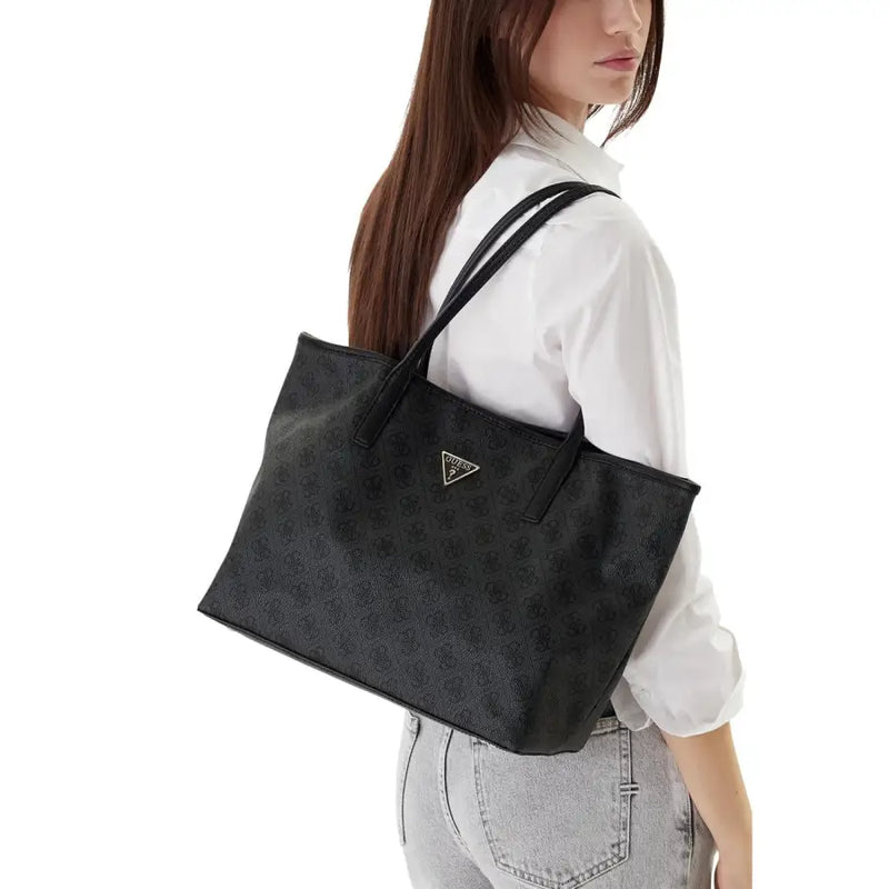 Black textured Guess grey print polyurethane tote bag with repeating logo pattern and gold-tone triangular emblem