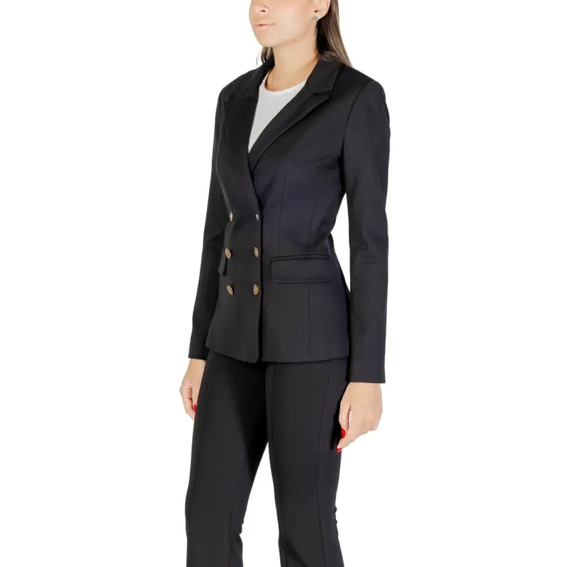 Women wearing Guess long black V neck blazer and matching trousers for fall winter fashion