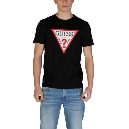 Schwarz Guess Männer t-shirt mit einem auffälligen roten und weißen dreieckigen Logo, dem Markennamen und dem Schriftzug „Waschungen Jeans“.