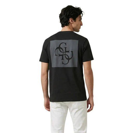 Rückseite schwarz Guess Männer t-shirt mit grauem rechteckigem Aufnäher mit aufwendigem schwarzem Monogramm-Design
