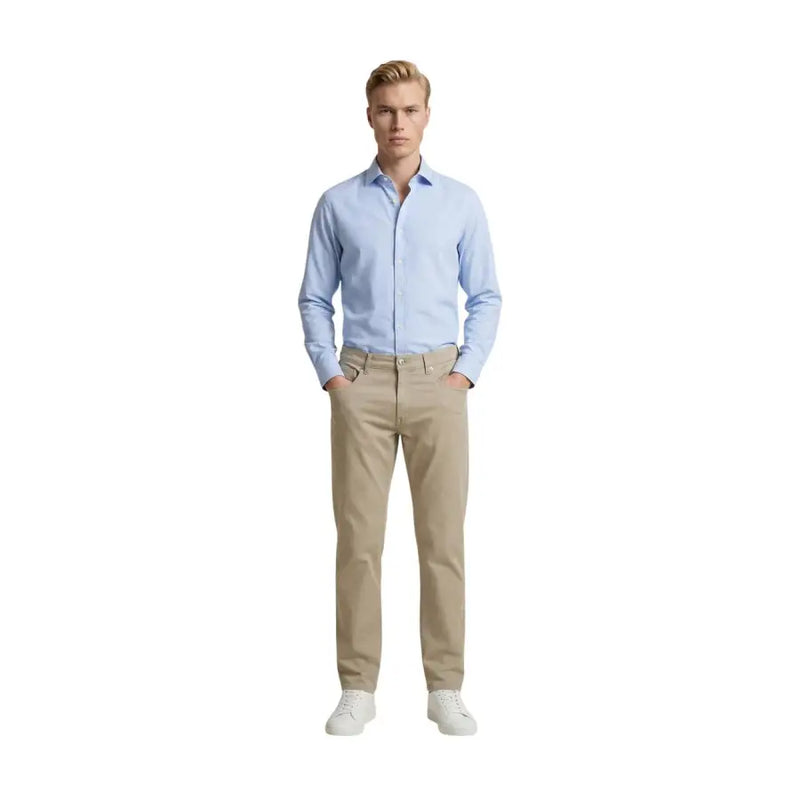 Ein Mann in Beige Guess Schmal geschnittene Baumwollmischhose kombiniert mit einem hellblauen Button-Down-Hemd