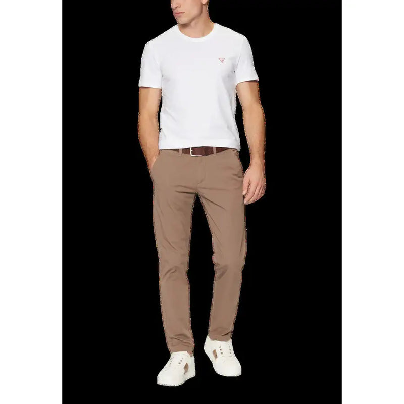 Eine beigefarbene, schmal geschnittene Chinohose mit dezenter Bügelfalte, getragen von einem Model mit guess weißes Herren-T-Shirt mit Rundhalsausschnitt