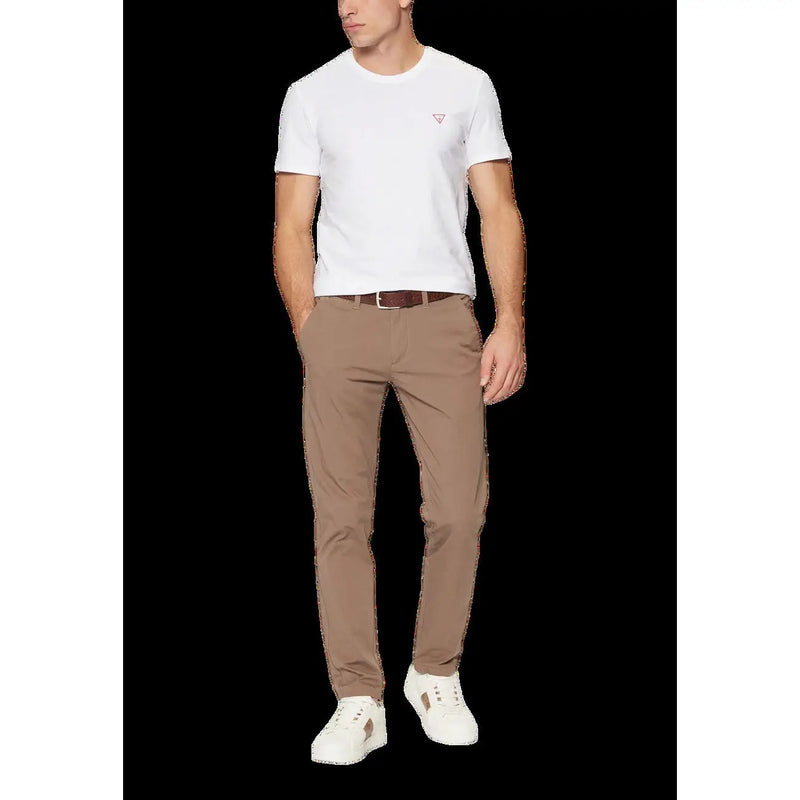 A pair of beige slim fit chino trousers with subtle creasing worn by a model with a guess men’s white round neck t shirt