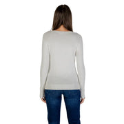 Light gray long-sleeved women’s top with rhinestone embellishments paired with blue jeans