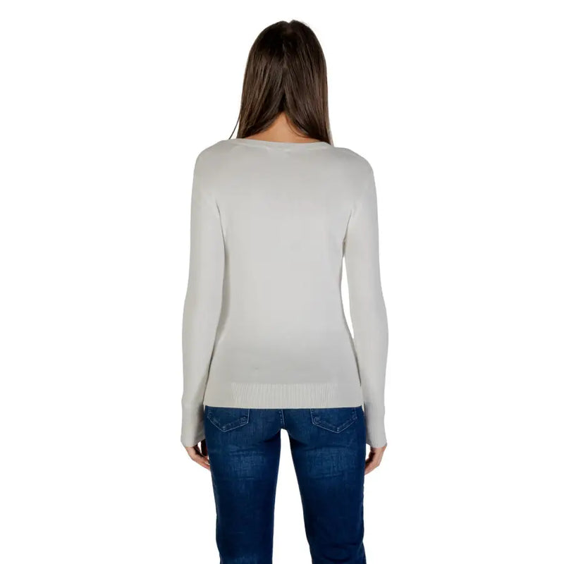Light gray long-sleeved women’s top with rhinestone embellishments paired with blue jeans