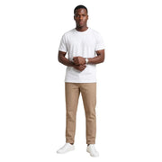 Ein Mann trägt beige gestreifte Baumwollhosen von Hydra Men und ein weißes, kurzärmeliges T-Shirt mit Rundhalsausschnitt. t-shirt und weiße Turnschuhe