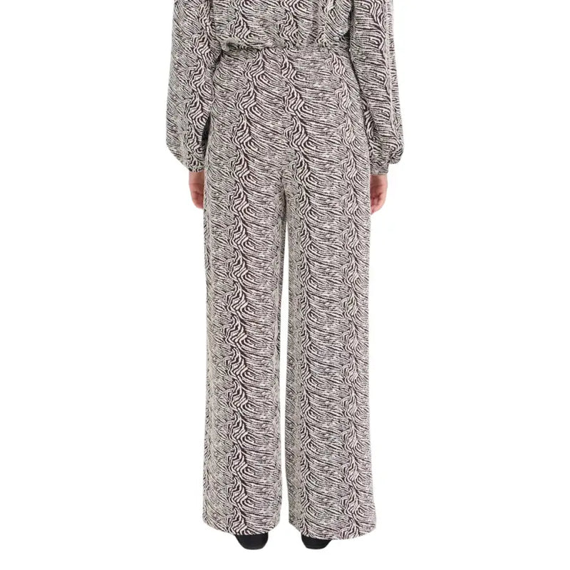 A woman wearing ichi women brown print trousers with a black and white patterned jumpsuit from fall winter collection