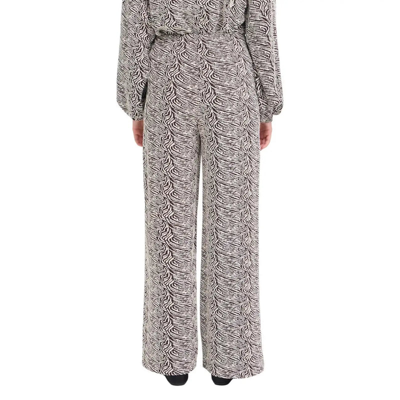 A woman wearing ichi women brown print trousers with a black and white patterned jumpsuit from fall winter collection