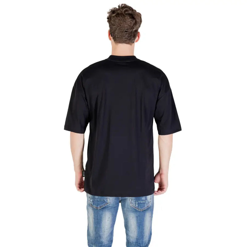 Person from behind wearing a black oversized T shirt and blue distressed jeans for Icon Black Men T Shirt Fall Winter Round Neck