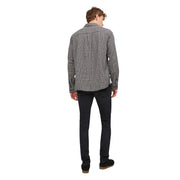 A man wearing a black and white plaid long-sleeved shirt with button-up collar and Jack and Jones men’s black jeans