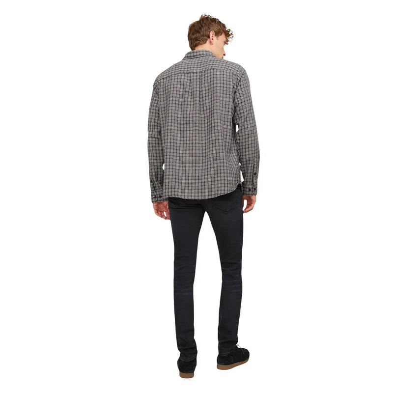 A man wearing a black and white plaid long-sleeved shirt with button-up collar and Jack and Jones men’s black jeans