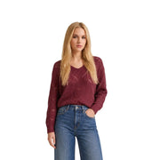 Ein bordeauxroter Strickpullover mit V-Ausschnitt und aufwendigem Zopfmuster von Jacqueline De Yong Damen-Strickkollektion mit blauem Glitzer
