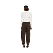 Eine Frau trägt braune Baumwolljeans von Jacqueline De Yong, kombiniert mit einem cremefarbenen Strickpullover. top