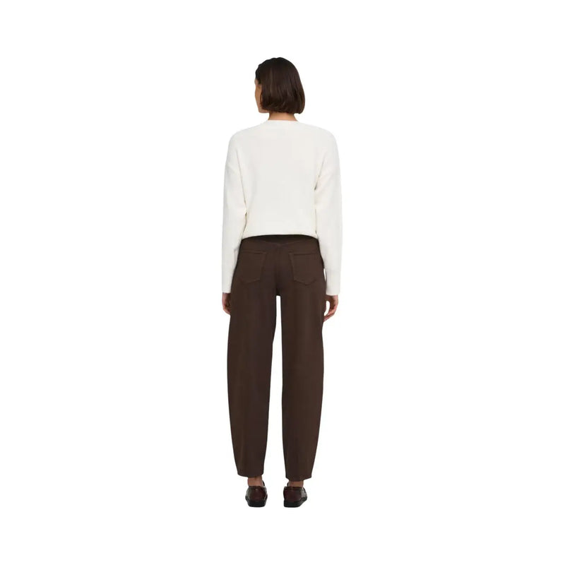 Eine Frau trägt braune Baumwolljeans von Jacqueline De Yong, kombiniert mit einem cremefarbenen Strickpullover. top