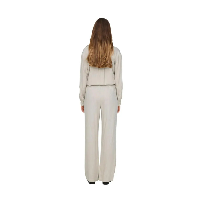 Eine Frau, die eine graue Leinenhose von Jacqueline De Yong in regulärer Passform trägt, wird von hinten mit einem cremefarbenen Outfit gezeigt. top