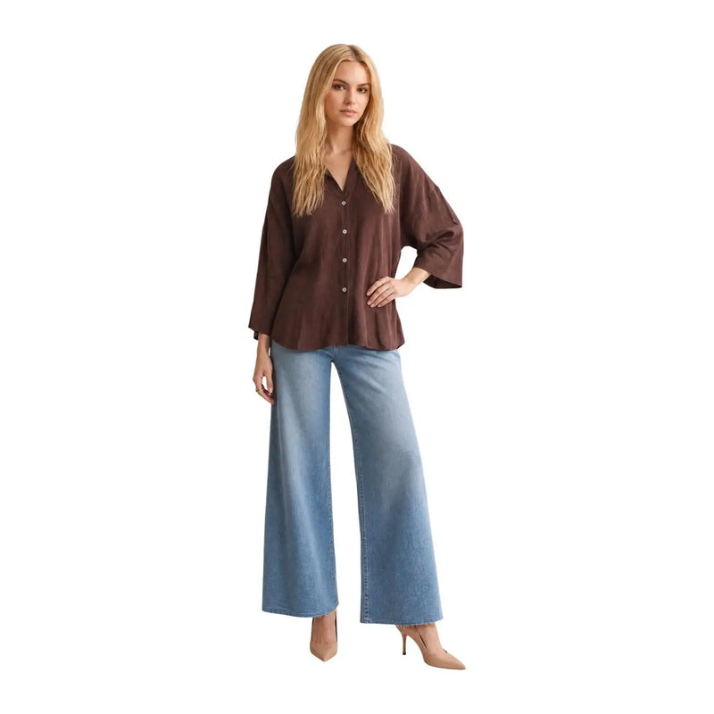 A woman wearing a JDY women brown viscose round neck classic shirt with wide sleeves and light blue denim trousers