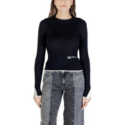 Women wearing black ribbed long-sleeve top with white trim and dark gray patchwork jeans
