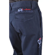 Rückseite einer dunkelblauen La Martina Herrenhose mit gestickten roten, weißen und grauen Logos an Tasche und Oberschenkel
