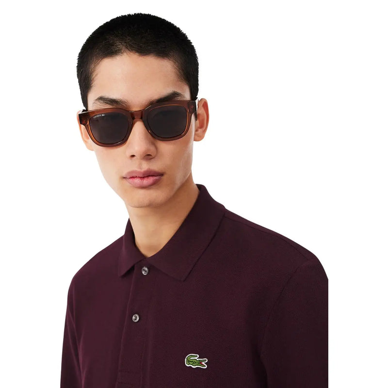 Braune Lacoste-Sonnenbrille mit Schildpattrahmen und dunklen Gläsern, kombiniert mit einem lila Lacoste-Herren-T-Shirt aus Baumwolle.