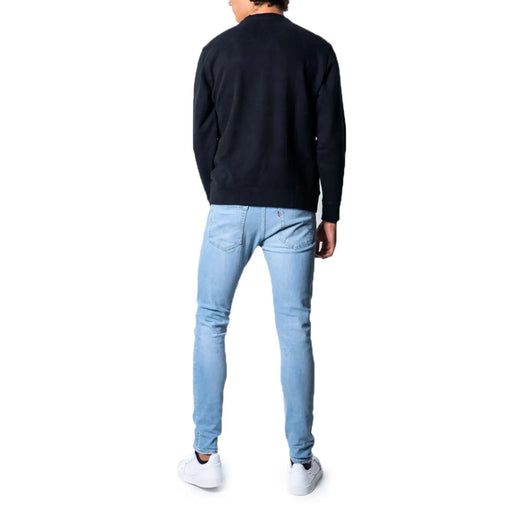 Hellblaue Jeans mit schmal geschnittenem, schwarzem Levi's Herren-Sweatshirt aus Baumwolle mit Rundhalsausschnitt, von hinten gesehen