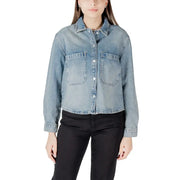 Woman wearing light-wash denim button-up shirt with front pockets, stylish classic design