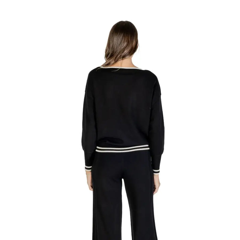 Woman wearing Liu Jo black long round neck knit sweater and pants with white stripe details