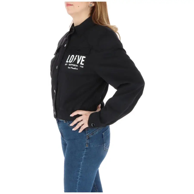 Women wearing a black long-sleeved denim jacket with white LOVE print and blue skinny jeans