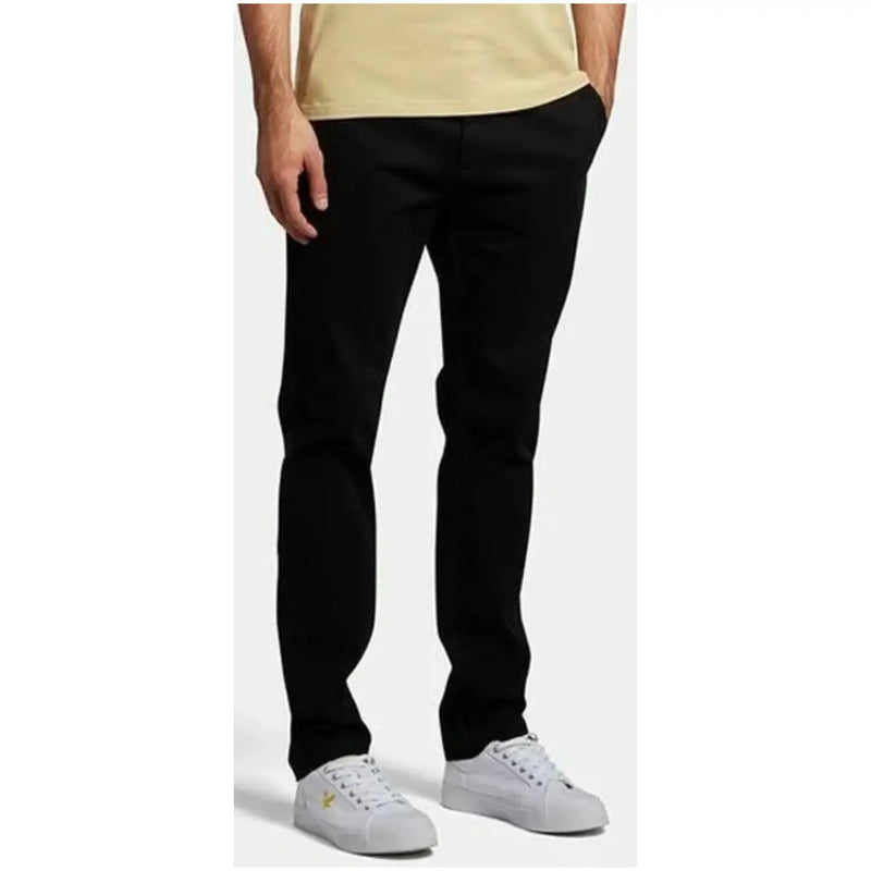 Lyle & Scott men’s black slim-fit cotton blend trousers with subtle gold logo paired with white sneakers