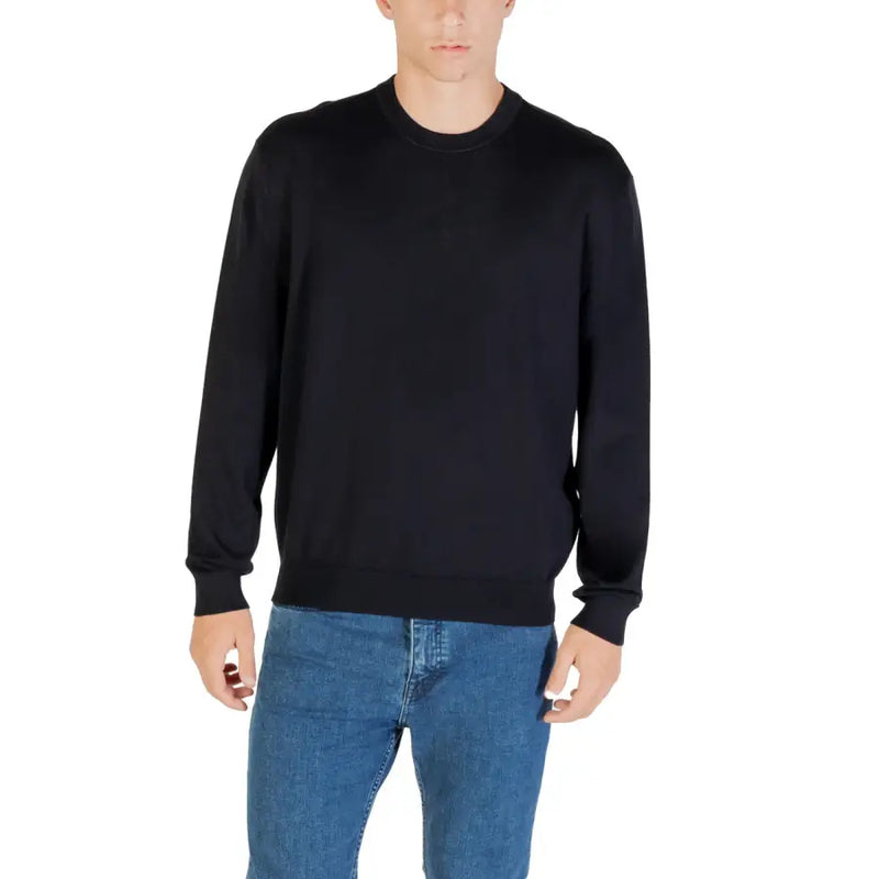 Man wearing Black Long Sleeved Crewneck Sweater and Blue Jeans in a casual setting
