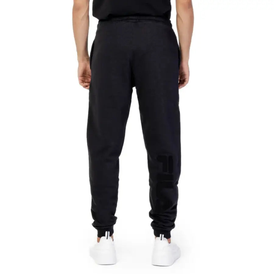 
                      
                        Fila men in black t-shirt and Fila Men Trousers posing for product showcase
                      
                    