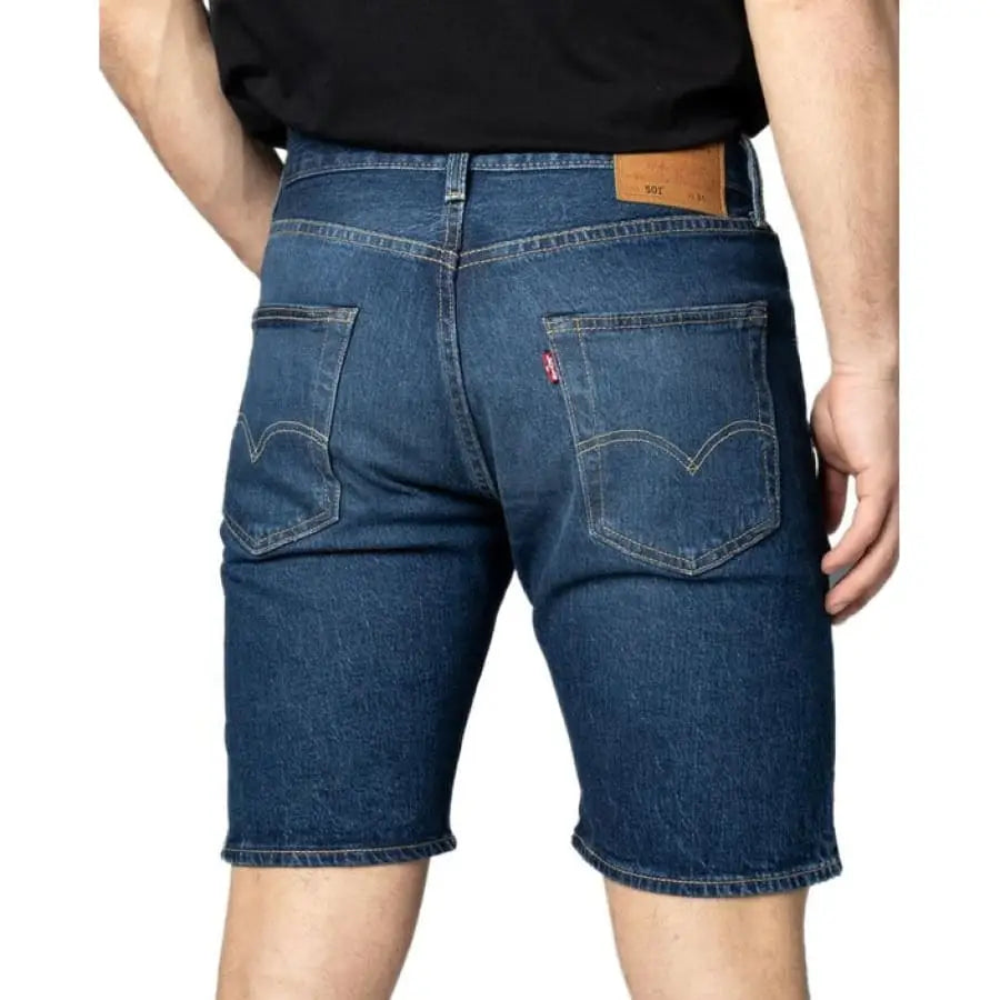 Man in Levi`s apparel, sporting black t-shirt and blue jeans men shorts.
