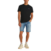 Male model in a black crewneck T shirt and denim shorts showcasing casual style
