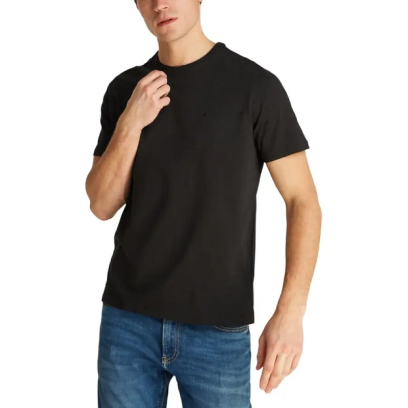 Male model wearing Mens Black Short Sleeve T Shirt and Blue Jeans in a casual setting
