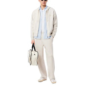 Man wearing casual beige outfit with a white tote bag and blue shirt appearance