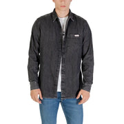 Man wearing a dark gray denim long sleeve shirt and blue jeans