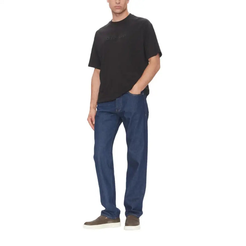 Man wearing a dark T shirt and blue jeans from the Black T Shirt Collection for Men