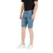 Man wearing denim shorts and white sneakers, showcasing casual summer fashion