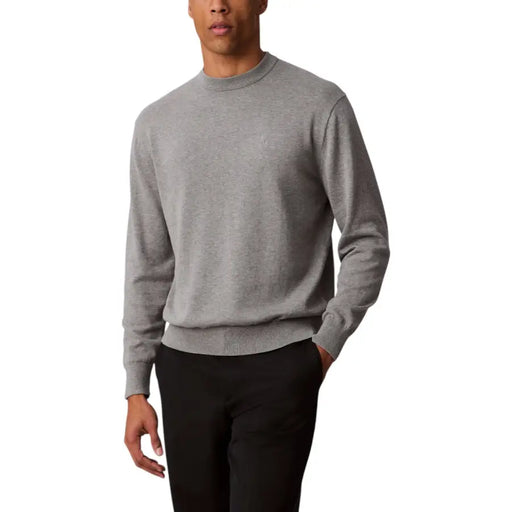 Man wearing a gray long-sleeved sweater and black pants for stylish men’s fashion