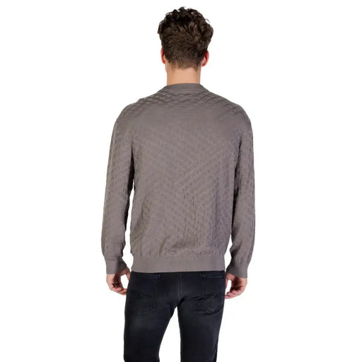 Man wearing a taupe patterned crewneck sweater and black jeans, showcasing stylish winter apparel