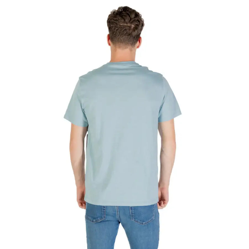 Man wearing a light blue Calvin Klein T shirt and jeans, showcasing casual style